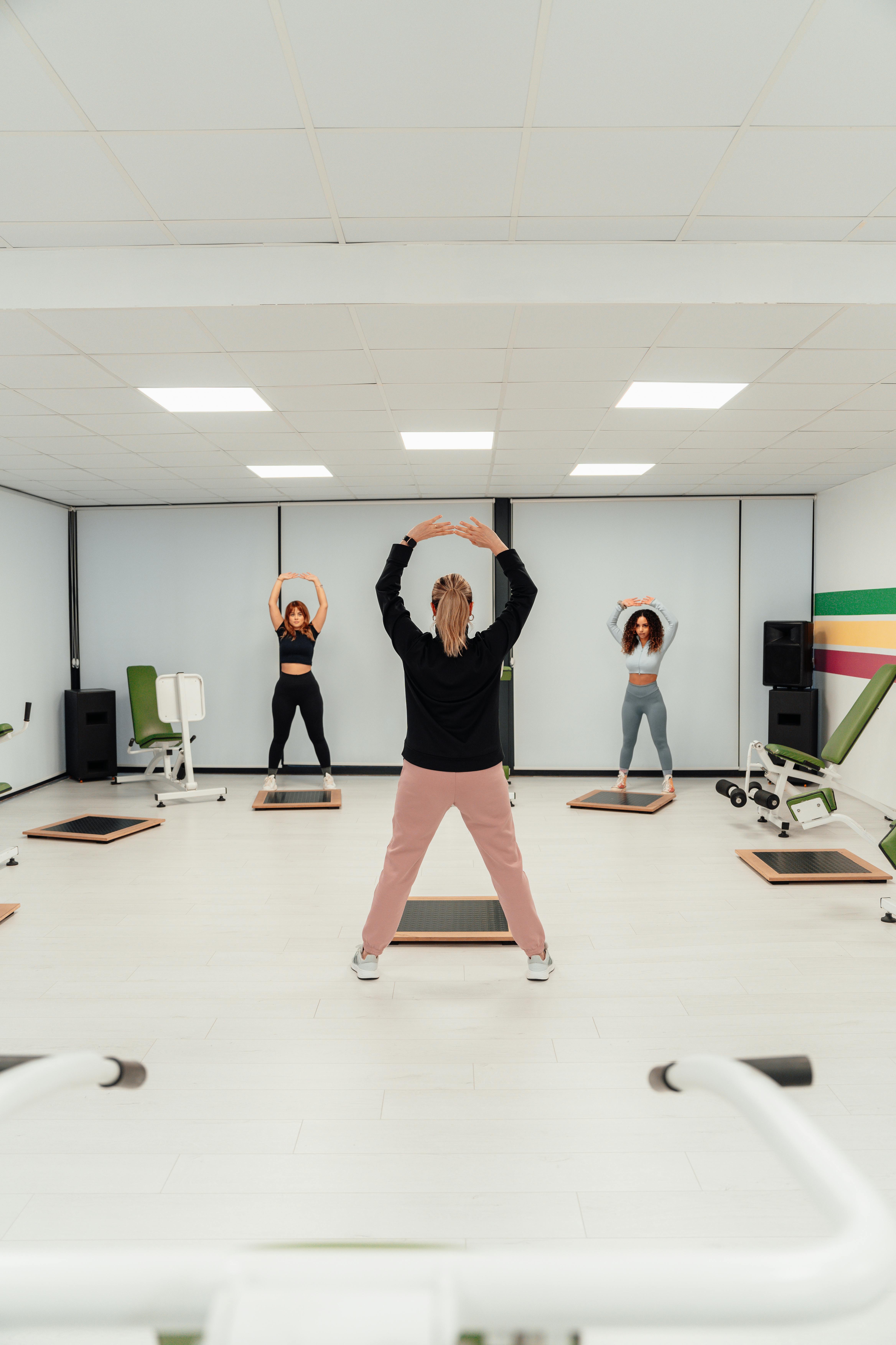 Women engage in a fitness routine in a bright, modern gym in Türkiye.