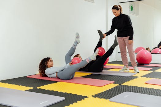 Women engaged in pilates class using pink balls and yoga mats indoors at a gym.