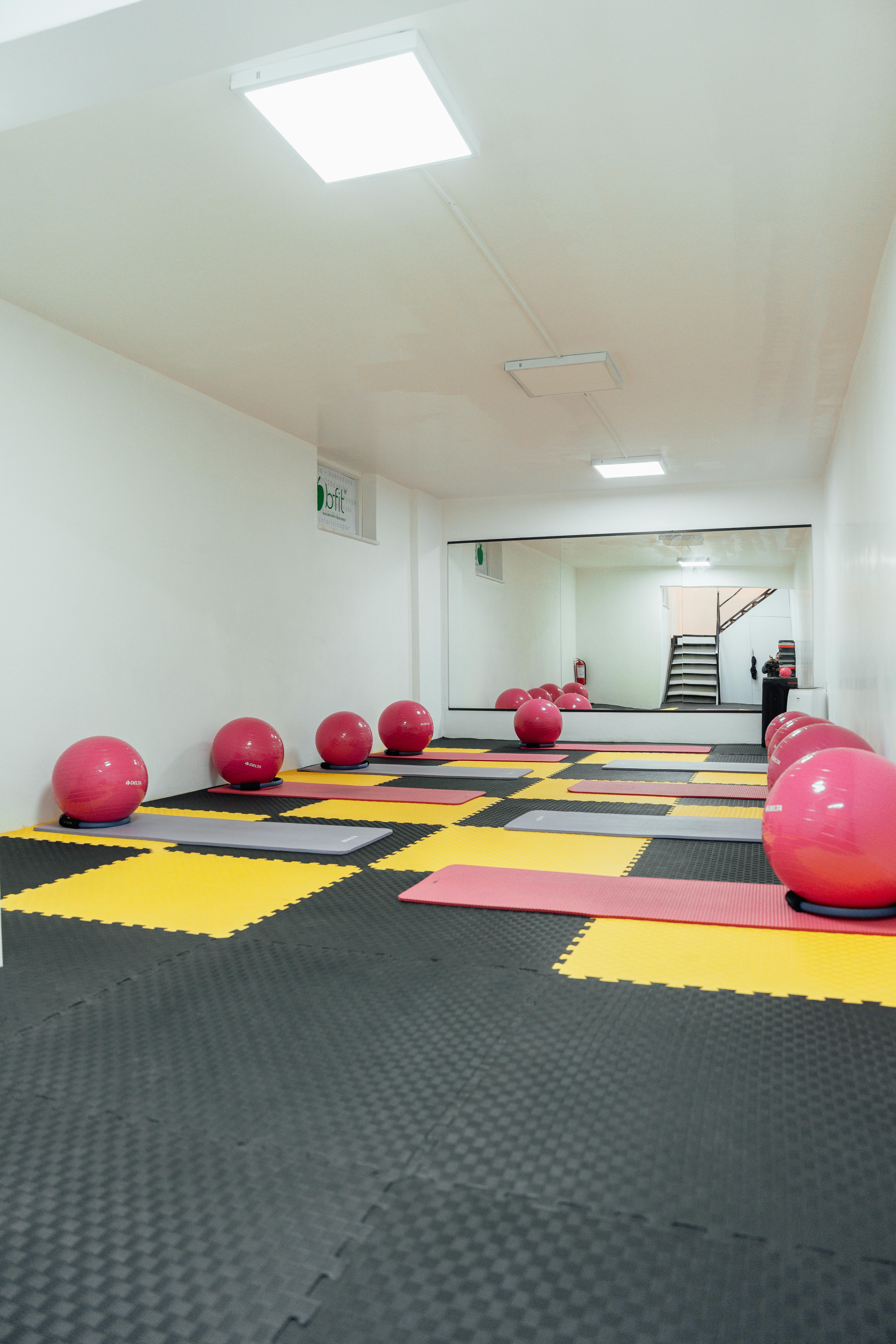 A modern, minimalist gym in Türkiye featuring yoga mats and colorful exercise balls for fitness activities.