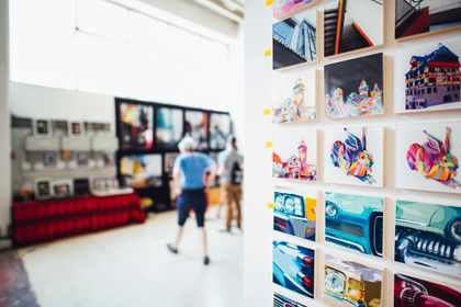 Visitors walking through a bright gallery of framed paintings — photo by Markus Spiske on Pexels