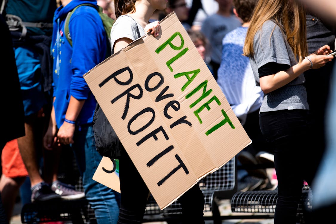 Women Holding a Planet over Profit Sign
