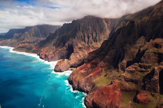 Stunning aerial view of the rugged Na Pali Coast, with dramatic cliffs and turquoise ocean in Kauai, Hawaii.