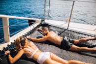 一对夫妇在夏威夷阳光明媚的游艇蹦床上晒日光浴，欣赏海景