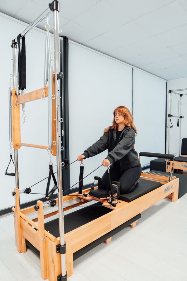 Mujer demostrando máxima extensión y control postural en sesión de pilates avanzado