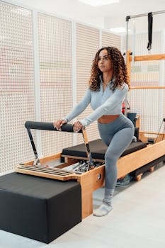 Woman exercising on pilates reformer machine indoors. Focus on fitness and wellbeing.