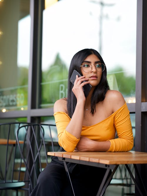 Free Photo of Woman Sitting by Table While Talking on Phone Stock Photo