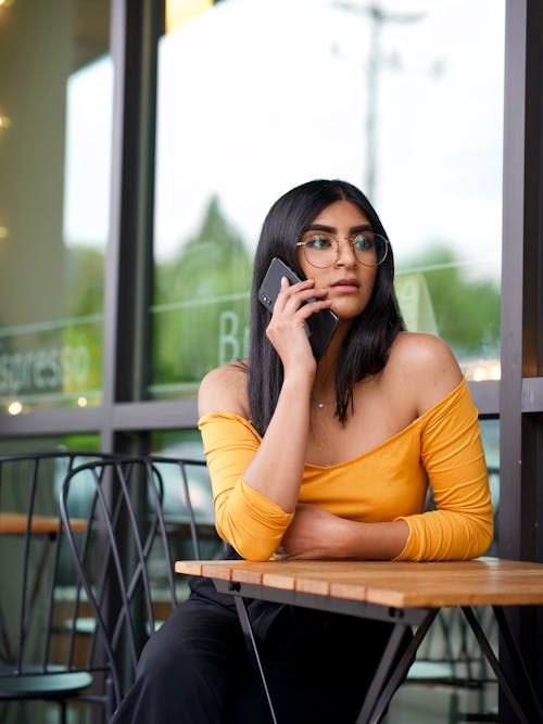 Foto Van Vrouw Zittend Aan Tafel Tijdens Het Praten Over De Telefoon