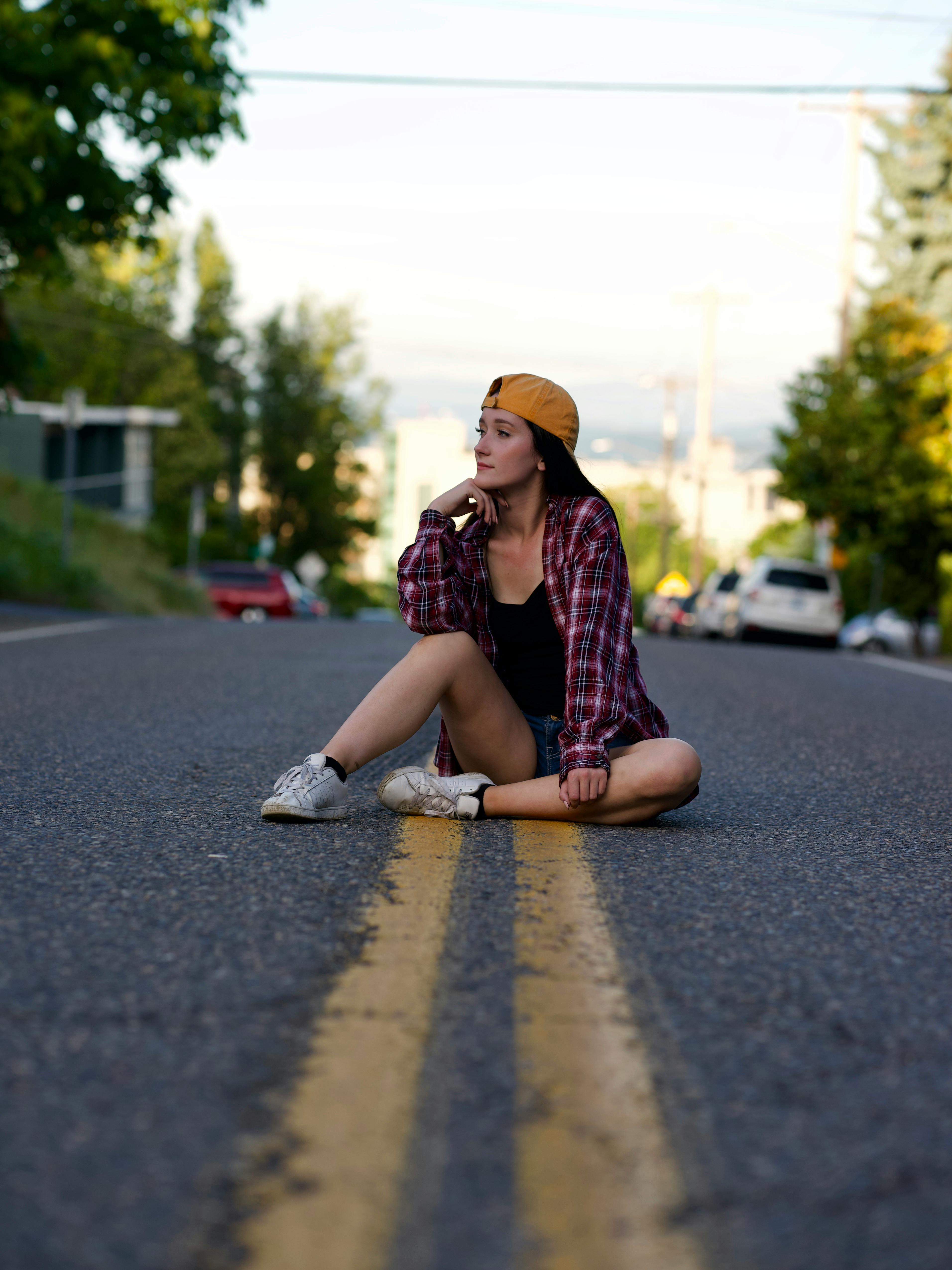 一位身着休闲装的年轻女子，正坐在城市道路上享受轻松时刻