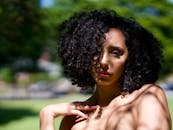 这幅户外肖像引人注目，描绘了一位卷发女性，戏剧性的阴影突显了自然之美