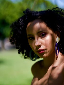 自然光线下，一位卷发、戴着精致耳环的女性在户外留下美丽的肖像