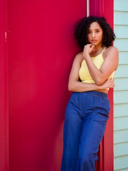 一位穿着休闲夏装的时尚女士，在红色门前自信地摆着姿势