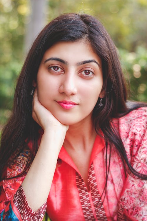 Portrait Photo of Woman in Red Top Posing with Her Hand on Her Cheek