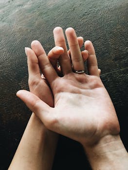 Intimate close-up of intertwined hands showcasing a ring against a dark background.