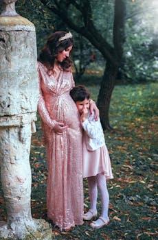 在宁静的秋季花园里，怀孕的母亲拥抱着身穿闪闪发光连衣裙的女儿