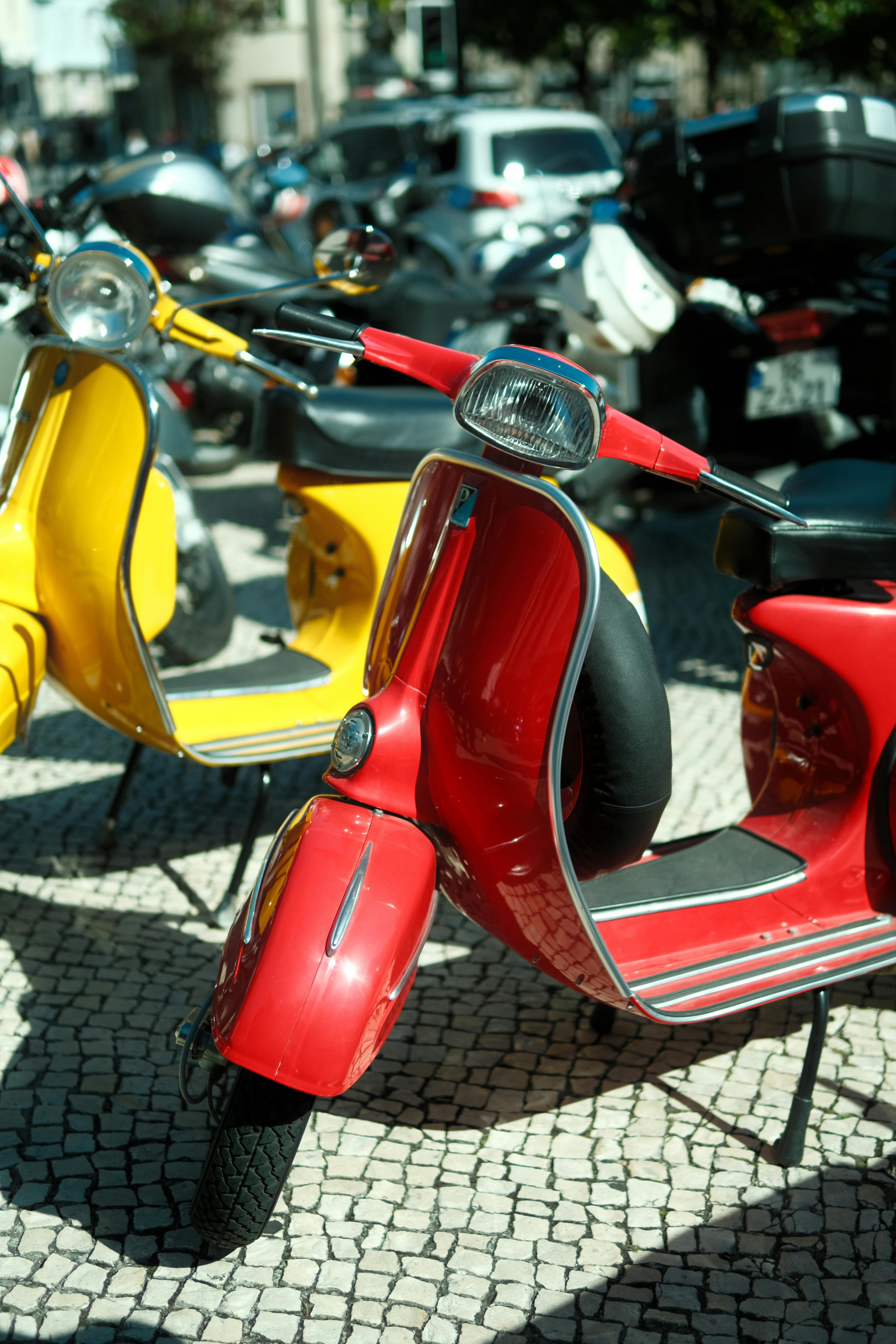 Free Red and yellow scooters parked on a cobblestone street in Porto, Portugal. Stock Photo