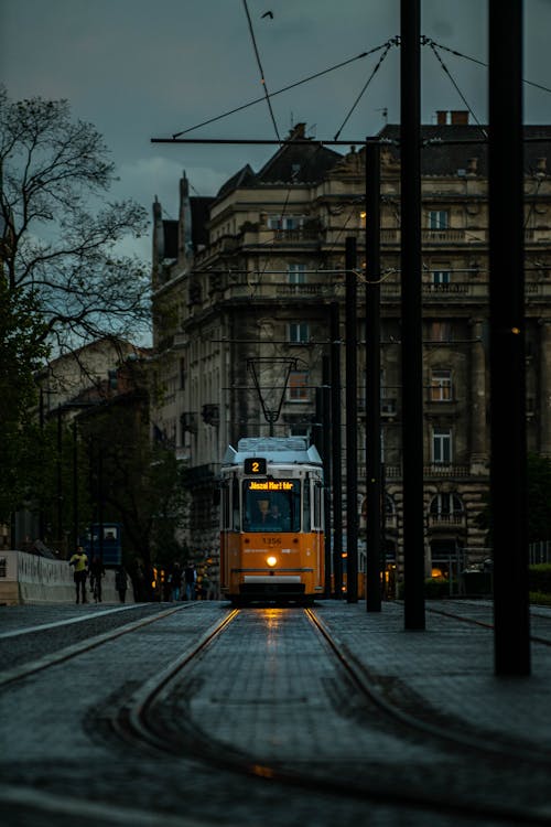A yellow train is traveling down a street