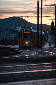 A vintage yellow tram travels through Budapest's cobbled streets at sunset, offering a glimpse into urban life.