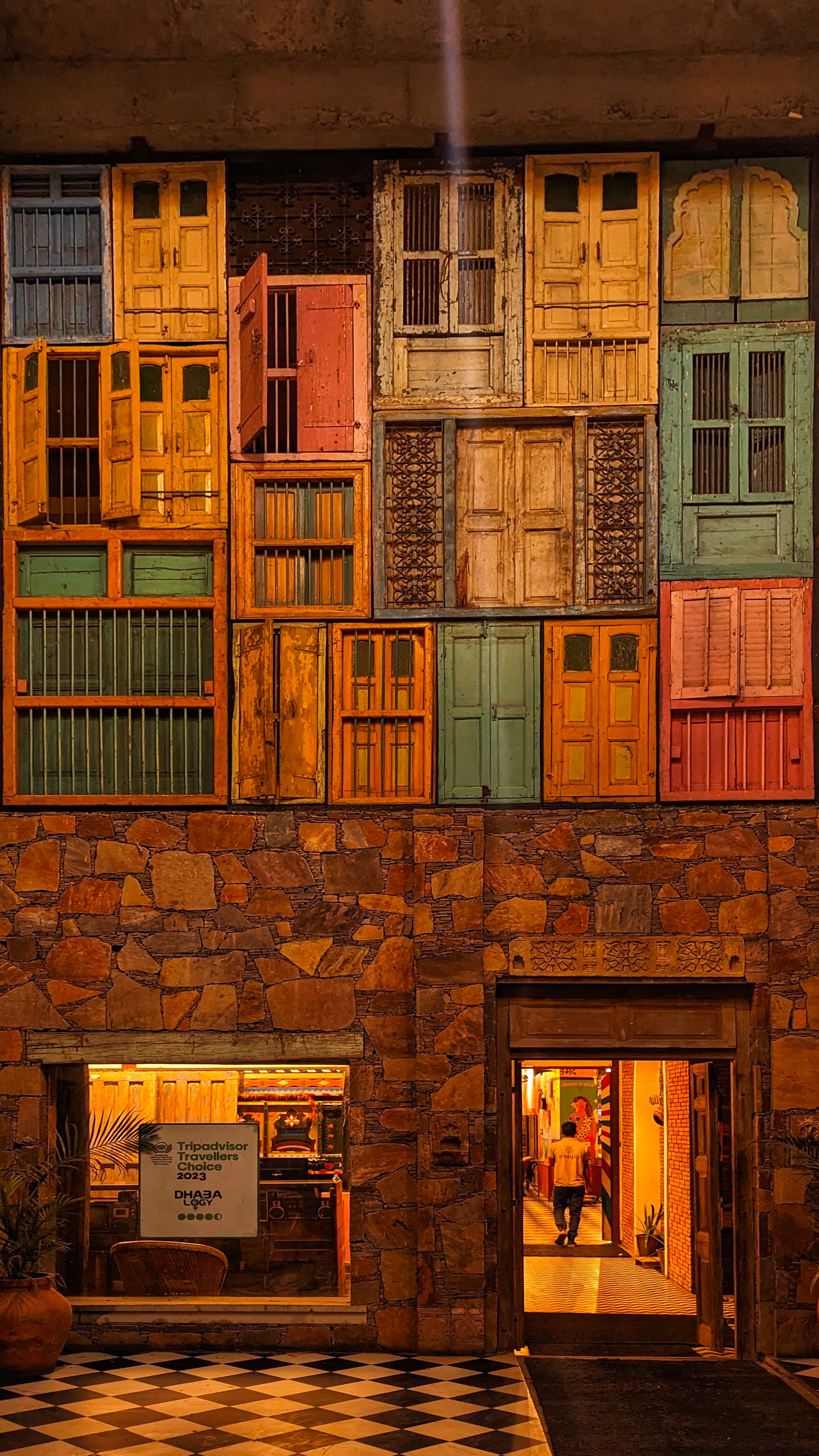 Unique facade with vibrant vintage doors and a rustic stone base, creating an artistic urban entrance.