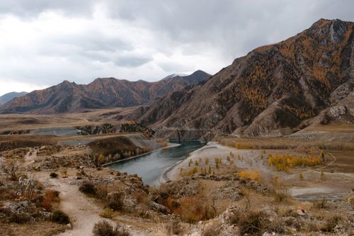 Free Breathtaking view of a serene river winding through the rugged Siberian mountains under a cloudy sky. Stock Photo