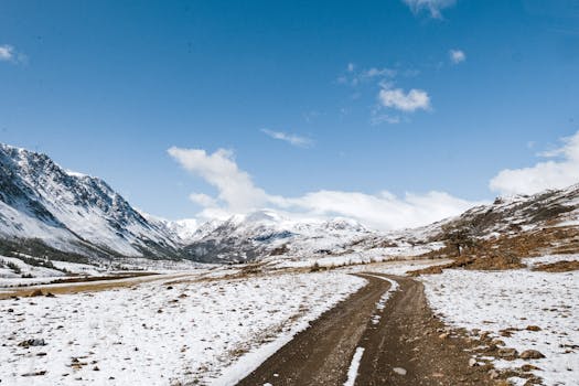 在蔚蓝的天空下，俄罗斯风景优美的雪山旁有一条土路