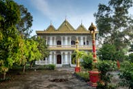 一座宏伟的传统寺庙，金色的屋顶被郁郁葱葱的绿植环绕