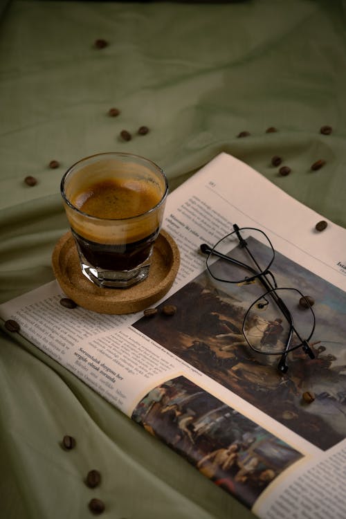 A cup of coffee and glasses on a bed