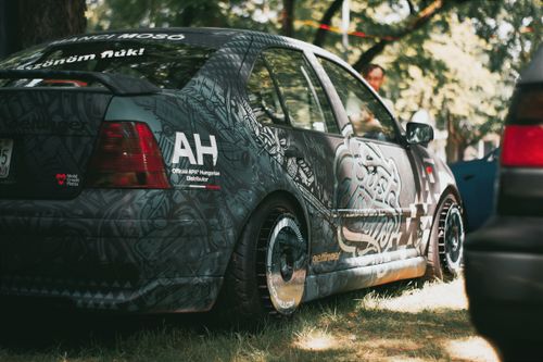 Free A creatively decorated car parked in a Hungarian park, showcasing unique graffiti art. Stock Photo