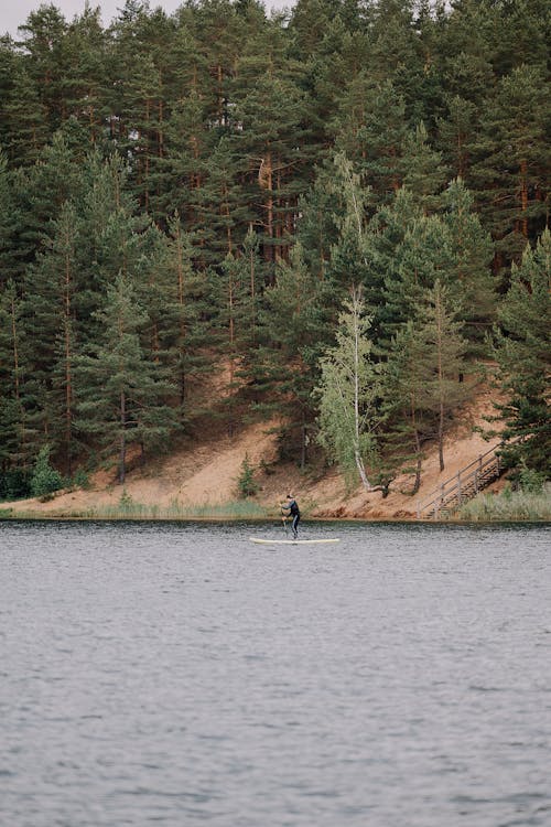 A person is standing on a paddle board in the middle of a lake