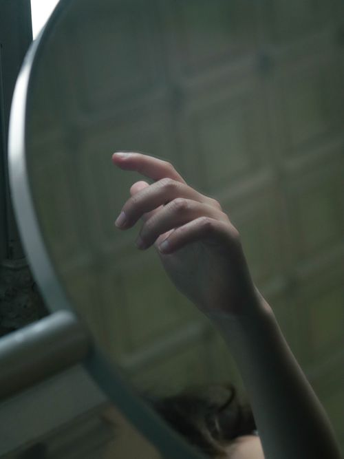 Free A close-up view of a hand reflecting artistically in a round mirror indoors. Stock Photo