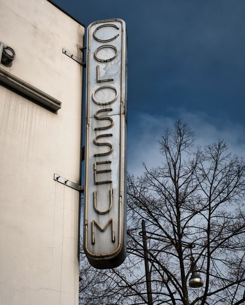 Free Vintage Colosseum cinema sign mounted on a building in Berlin, Germany with bare trees. Stock Photo