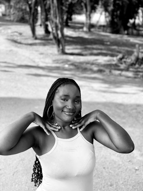 Free A joyful outdoor portrait of a woman with braided hair and a tank top. Stock Photo