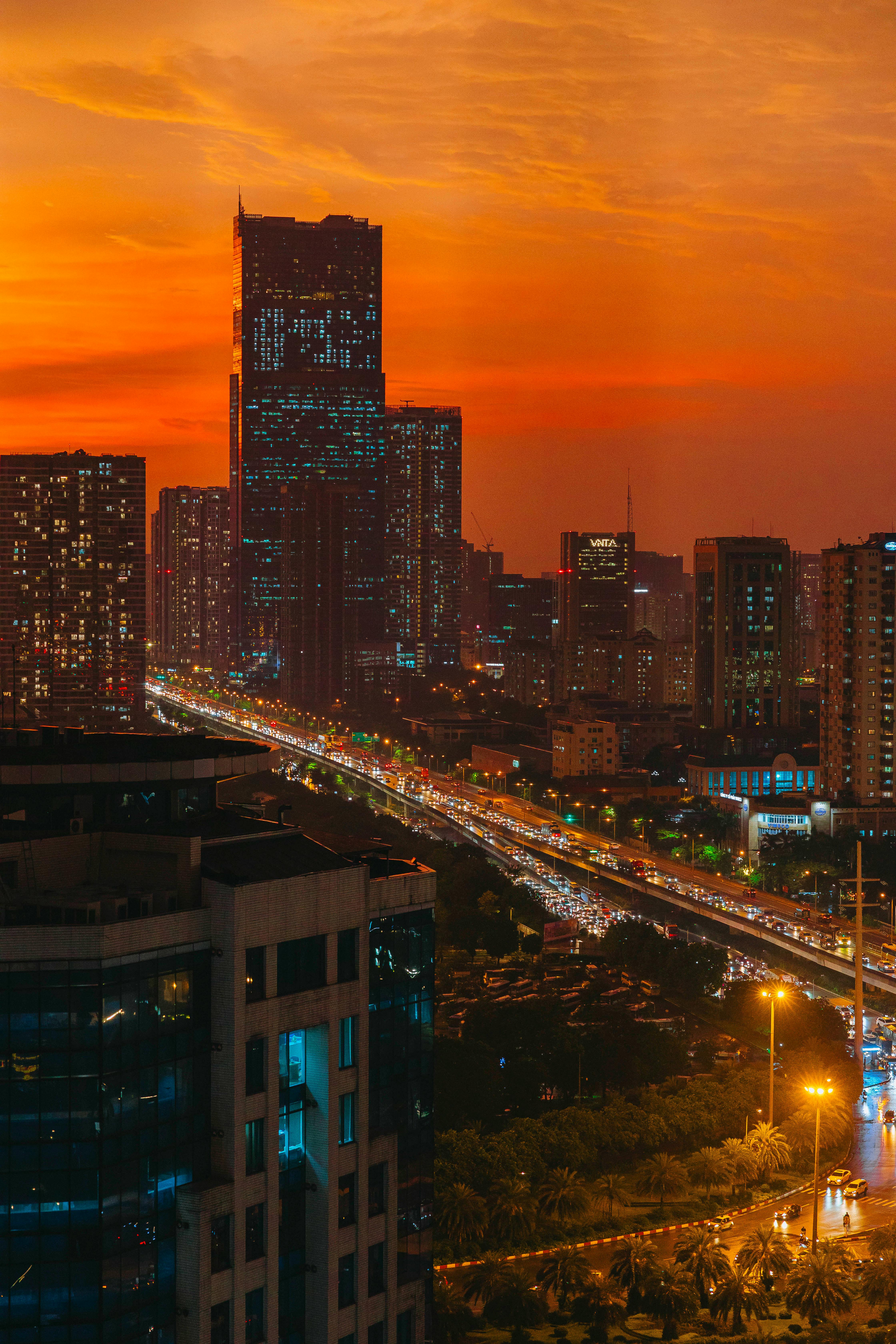 Stunning cityscape featuring skyscrapers at sunset, with vibrant traffic and a dramatic red sky.