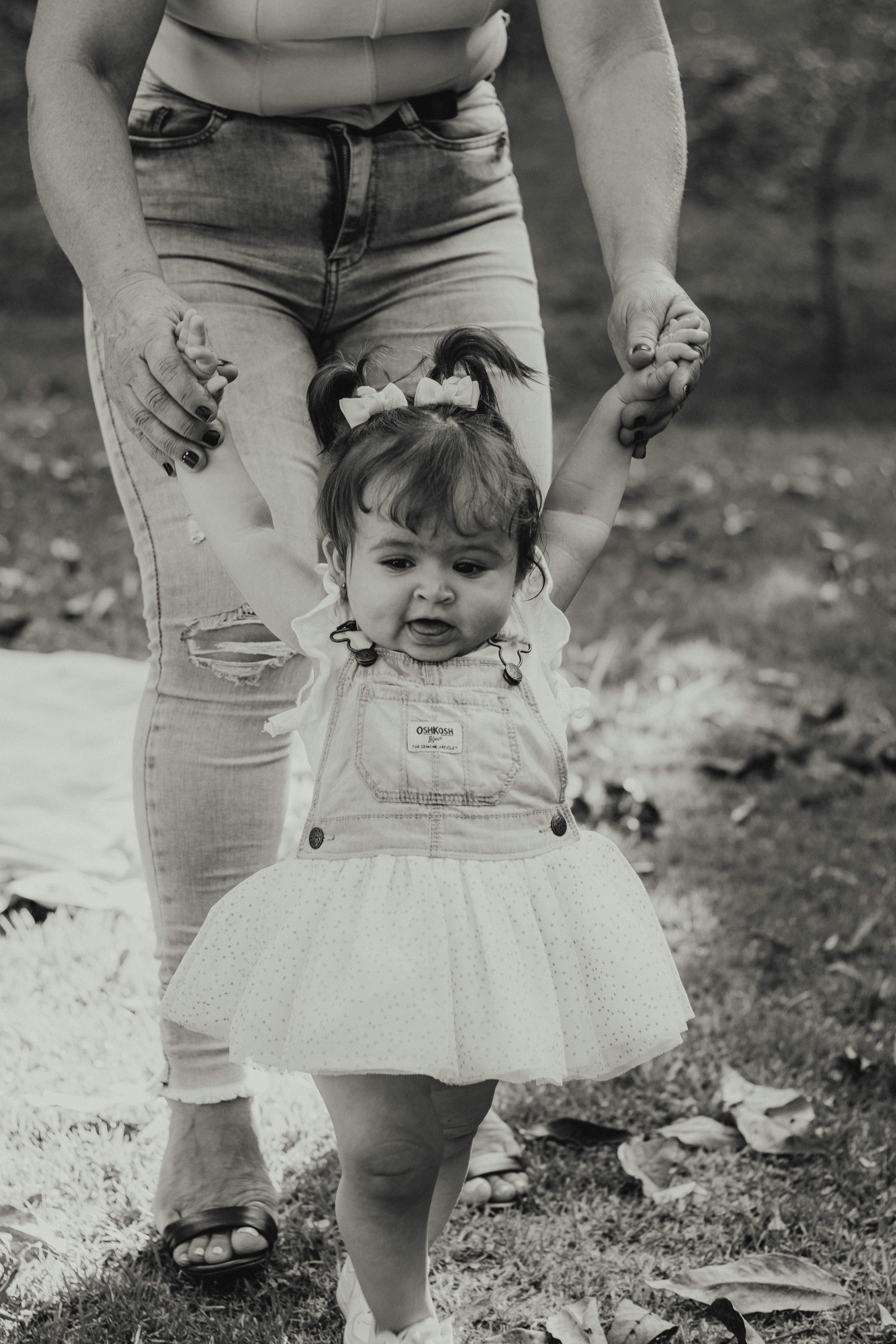 mother helping little daughter to walk