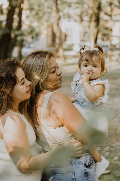Free A smiling grandmother, mother, and baby enjoying a sunny day in the park, showcasing familial love and bonding. Stock Photo