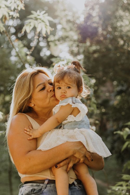 Free A heartwarming scene of a grandmother hugging her granddaughter in a sunny park. Stock Photo