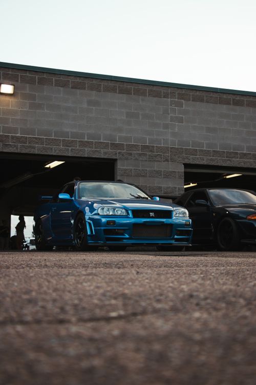 Free A vibrant blue Nissan Skyline GT-R parked in an urban garage setting during the day. Stock Photo