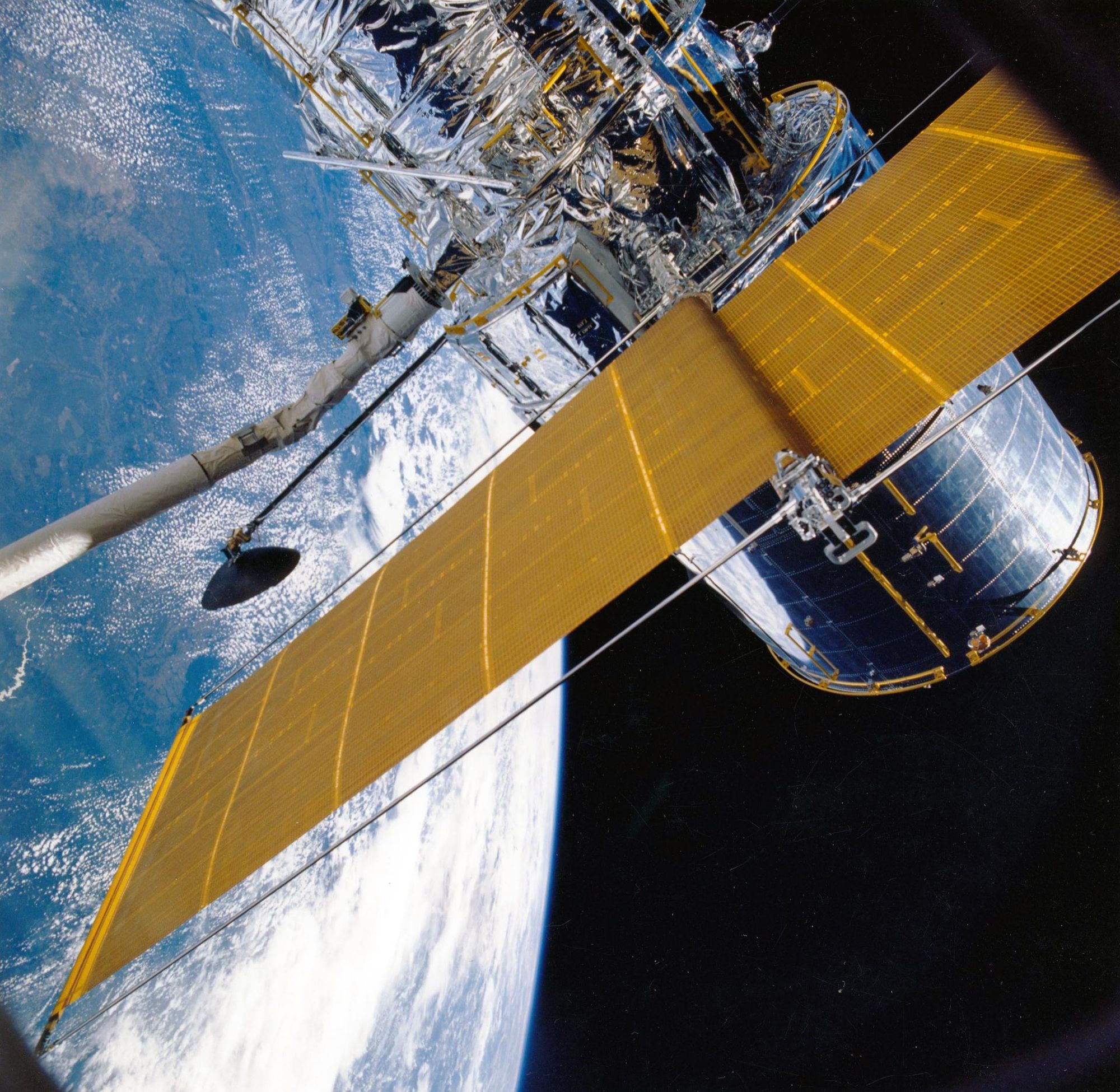 El telescopio espacial Hubble en órbita sobre la Tierra con sus paneles solares desplegados