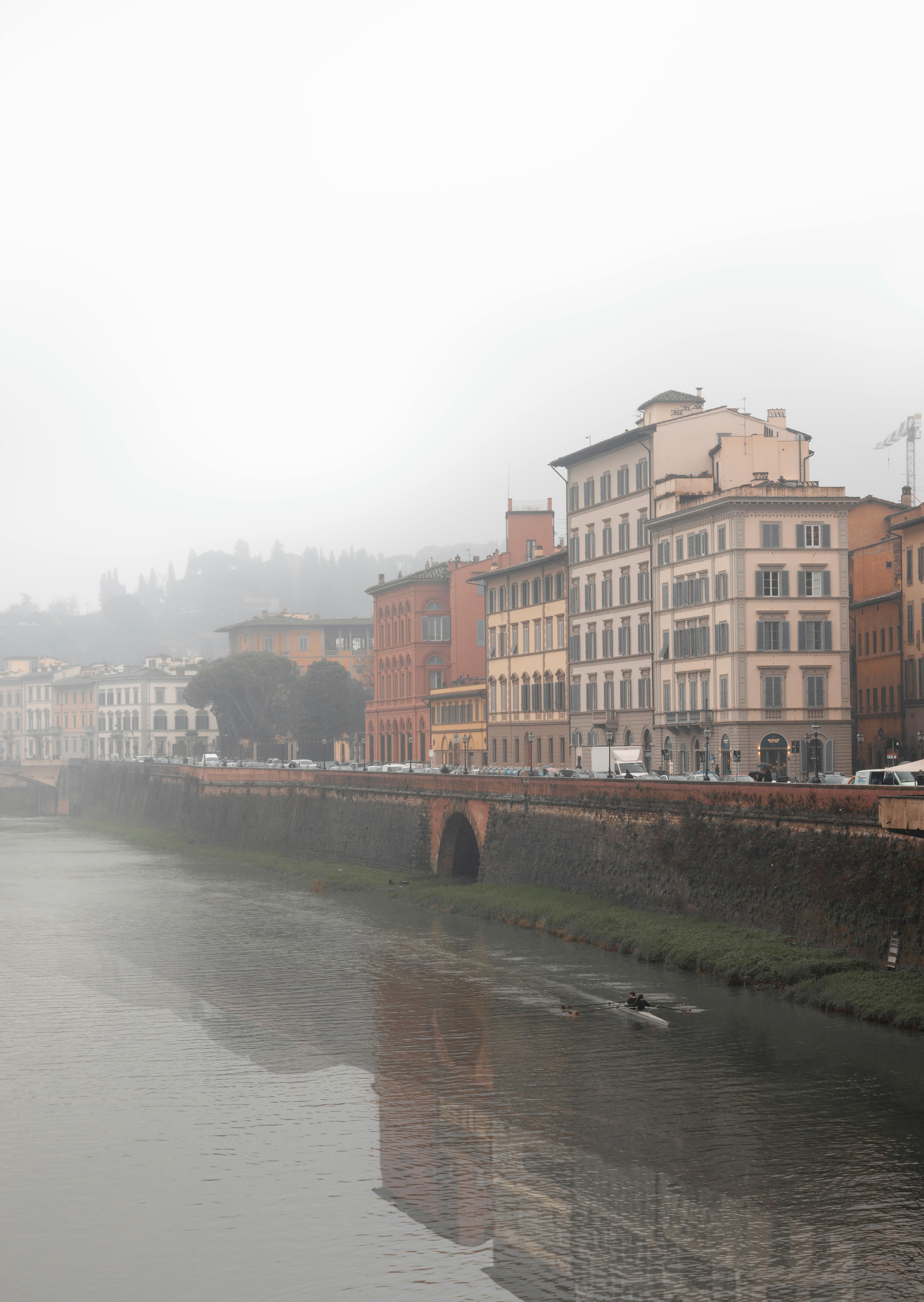 Scenic view of Florence's architecture along the Arno River on a foggy morning.