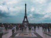 在巴黎多云的天空下，成群结队的游客在标志性的埃菲尔铁塔度过了一天