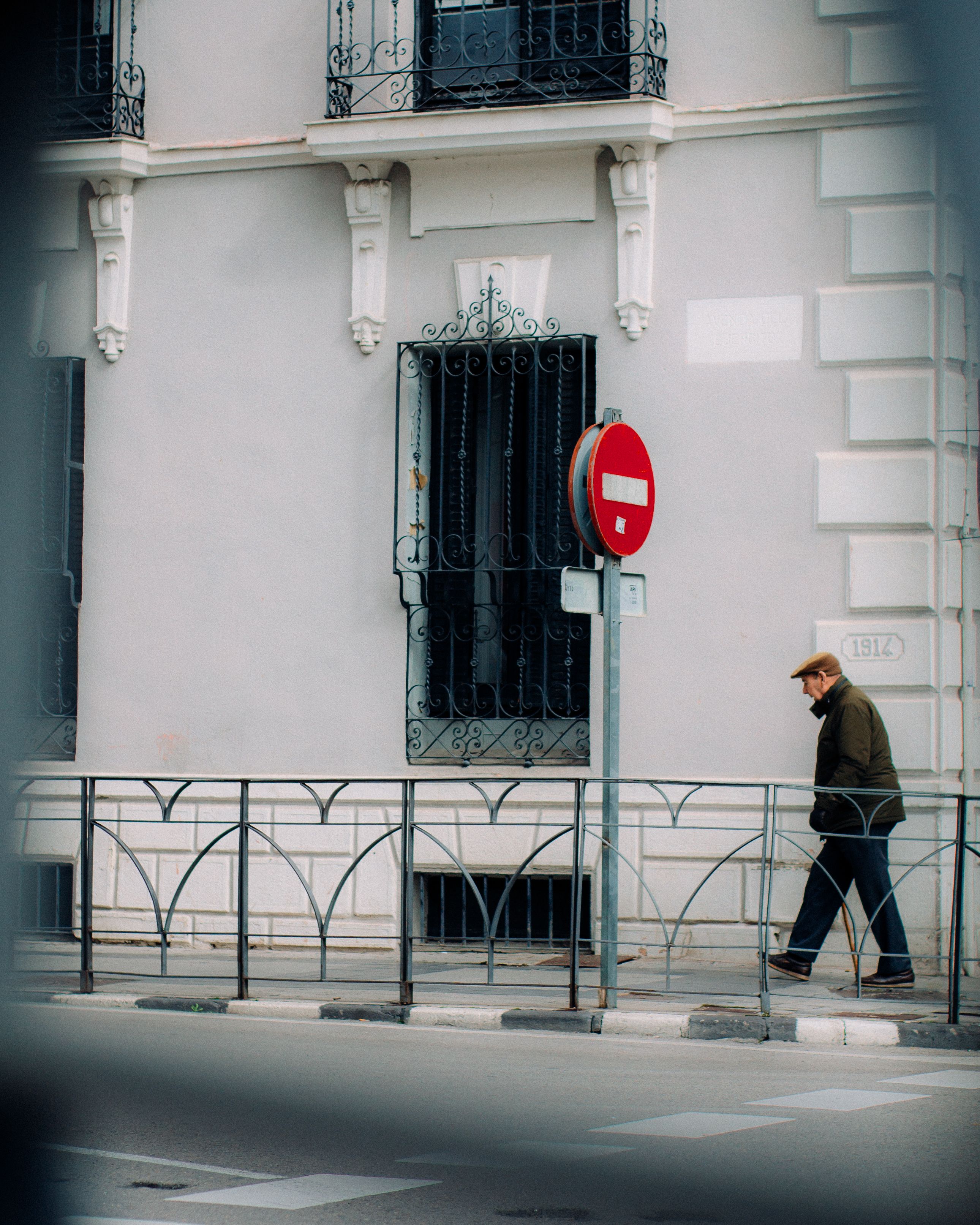 A Man Walking on the Sidewalk by the Building in a City · Free Stock Photo