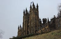 这是一座历史悠久的哥特式城堡的低角度视图，其突出的塔楼展现了精致的中世纪建筑风格