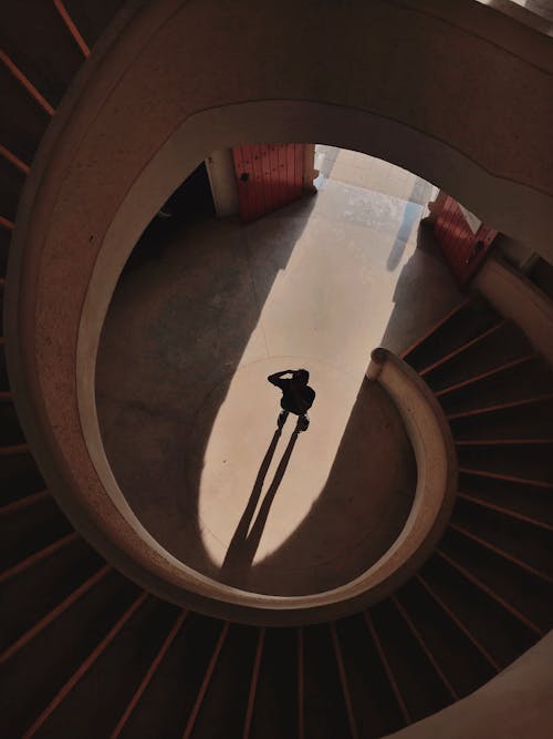 Person Standing Below A Spiral Staircase