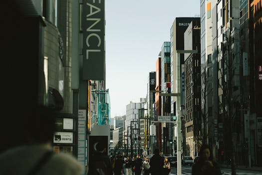 Explore a lively Tokyo street bustling with people and modern architecture under clear skies.