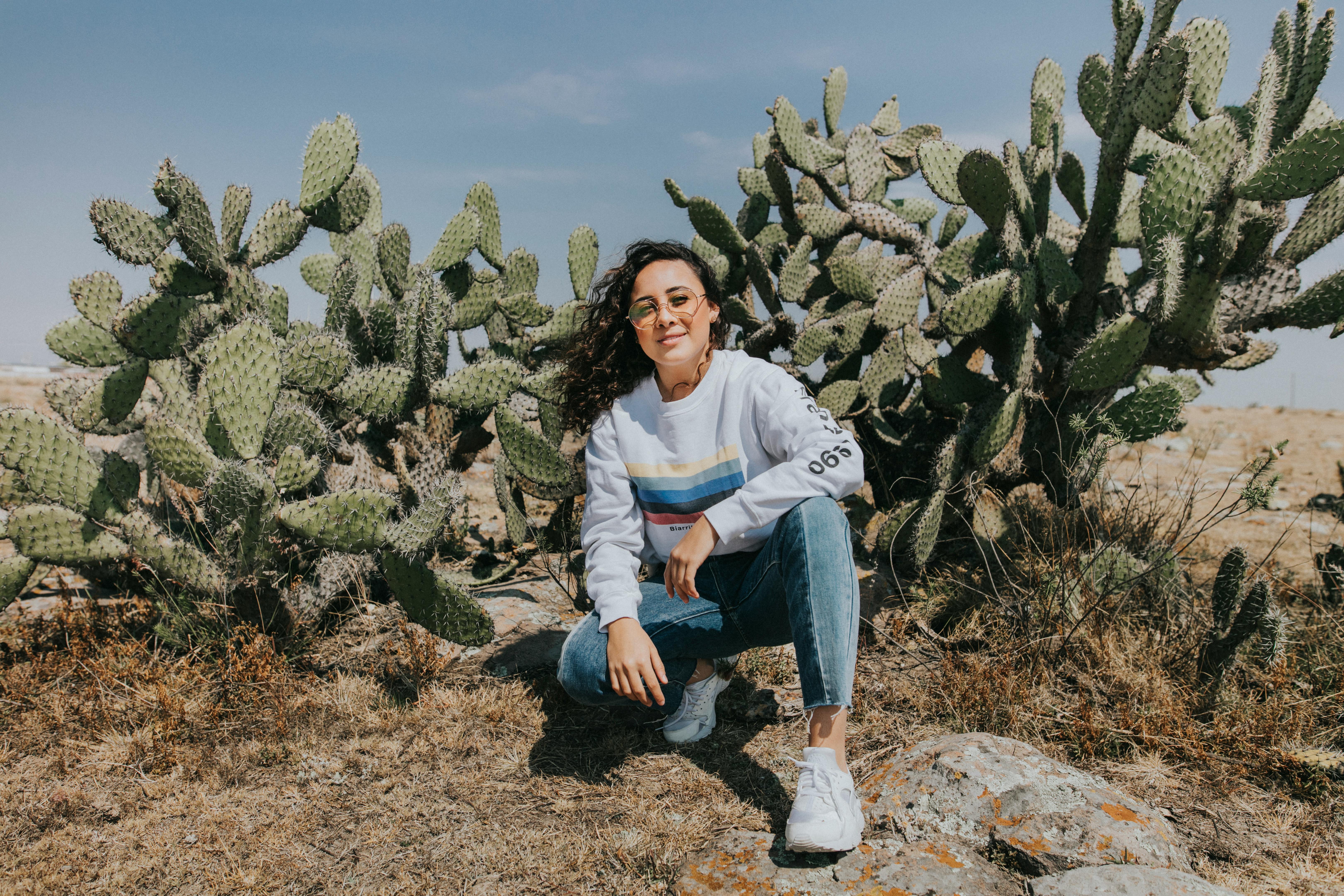 Woman crouching near a cactus