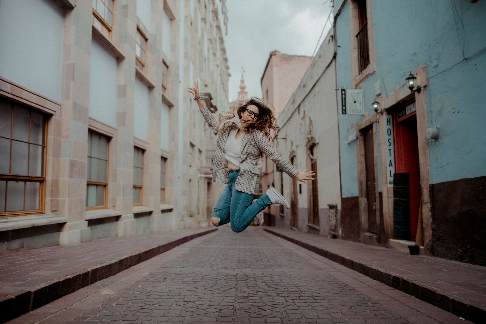zeolite for midlife energy crash — A stylish woman jumps joyfully in a vibrant city street, showcasing urban fashion.