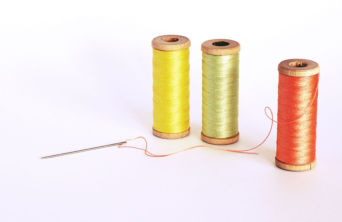 Vibrant spools of thread with a needle on a white background