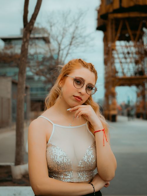 Free A stylish woman with eyeglasses poses thoughtfully in an urban industrial environment. Stock Photo