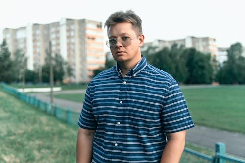 A man in glasses standing in front of a park