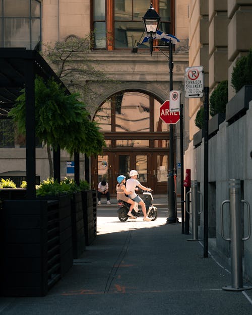 A man riding a scooter down a sidewalk