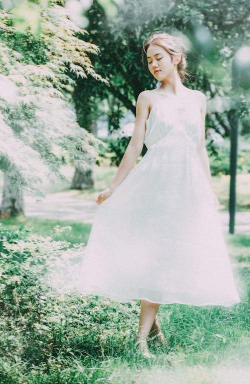 A woman in a white dress is standing in the grass